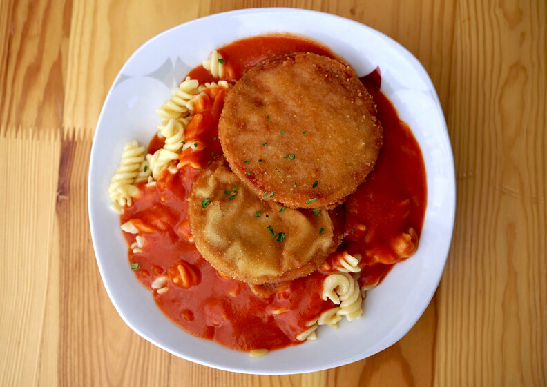 breaded Jagdwurst, fusilli noodles and tomato sauce on a plate