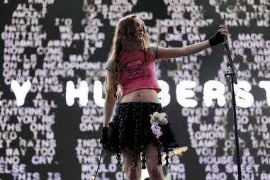 a female singer on stage wearing a pink shirt and black skirt