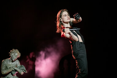 A woman performing on stage wearing all black and leaning backward