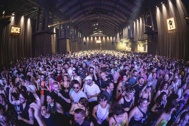 a crowd in what looks like an airport hangar, waiting for a band