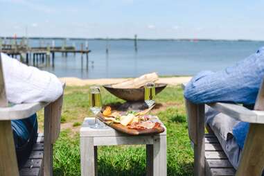 two people sitting in front of the maryland shoreline with a charcuterie board