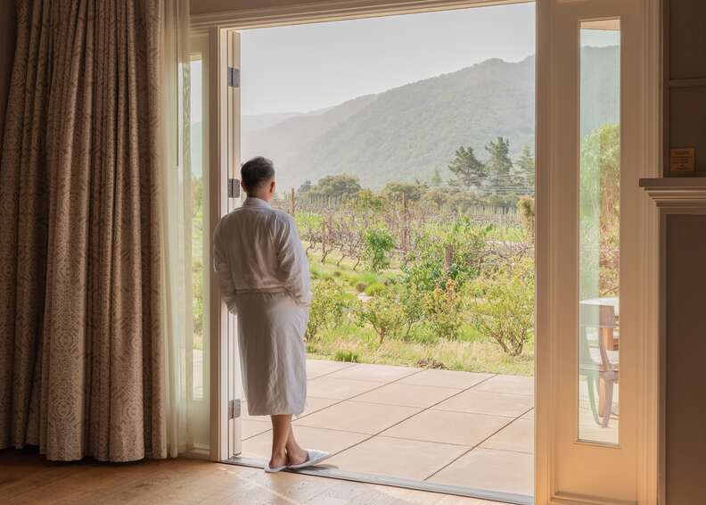 man in a robe standing in a doorway overlooking california vineyards in carmel