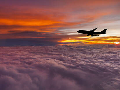 A plane flying among the clouds during a sunset. The latest flying safety report shows that flying is safer than ever.