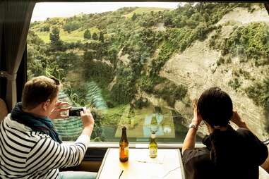 two people on a train taking photos out of the window in new zealand