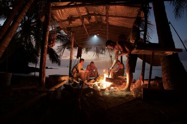 group of people building a shelter on a deserted island during overseas adventure travel