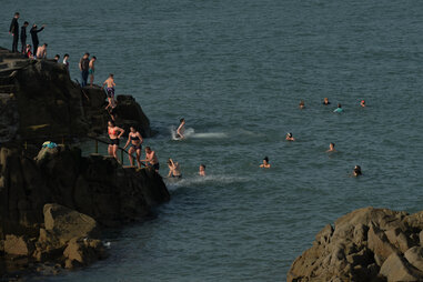 people jumping off cliff into open water in dublin for an adventure vacation