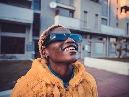 Girl looking at solar eclipse wearing the proper protective eyeglasses