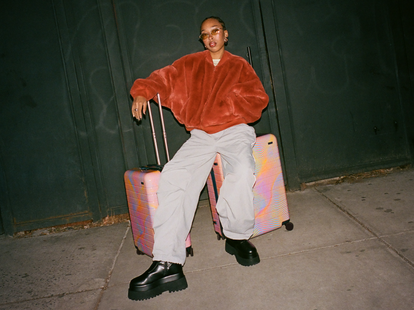 A woman sitting on the new Away Soundwave luggage connection.