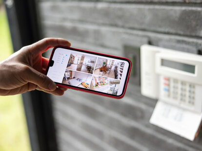 A woman watching the security cameras of her house on her cell phone