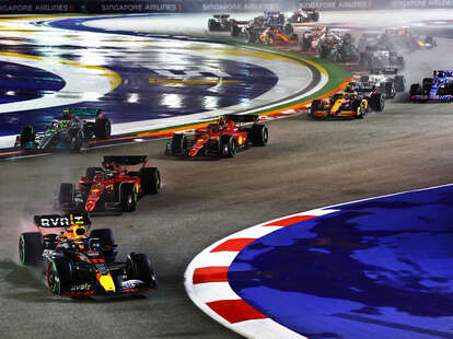 Sergio Perez of Mexico driving the (11) Oracle Red Bull Racing RB18 leads Charles Leclerc of Monaco driving the (16) Ferrari F1-75 and the rest of the field at the start during the F1 Grand Prix of Singapore. 