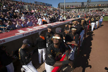 View of Salem-Keizer Volcanoes players wearing NASA eclipse glasses in dugout during game vs Hillsboro Hops at Volcanoes Stadium