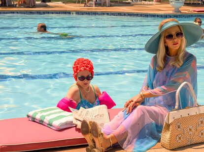 A still from the Apple TV+ miniseries &lsquo;Palm Royale&rsquo; showing two characters sitting poolside.