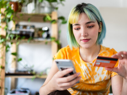 Young woman with colored hair shopping online with a credit card.