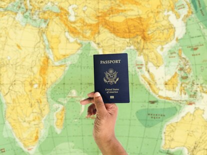 A person holding their passport in hand while standing in an airport.