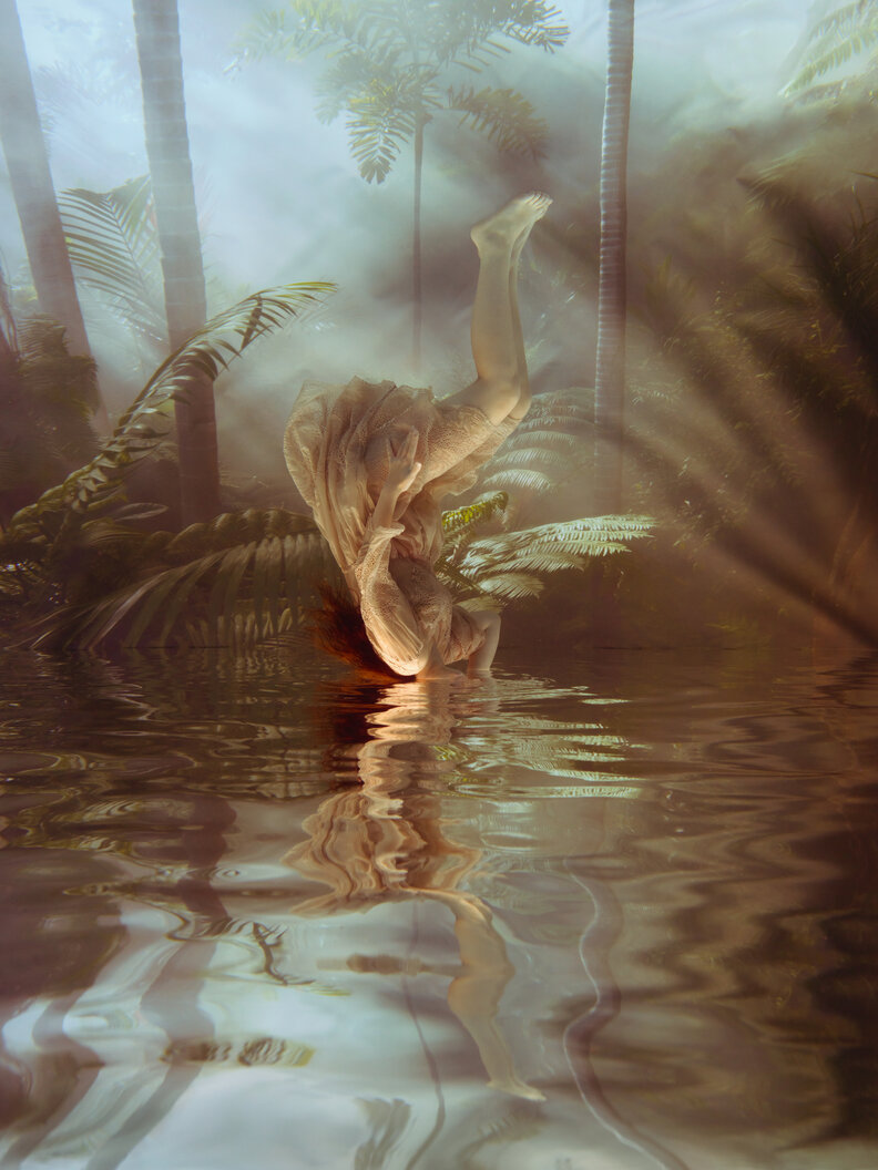 a fantastical image of an woman upended in a lake, not quite drowning