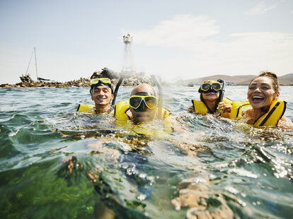 Medium shot portrait of smiling family on snorkeling tour in tropical ocean while on vacation.