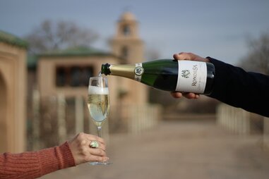 a hand pouring a bottle of Champagne on a wine road trip