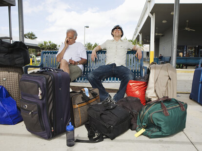 Two men with luggage sitting in airport area