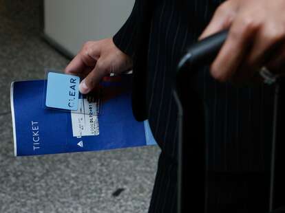 A traveler holds her ticket and Clear security fast pass card as she waits demonstrate the Clear express security lane