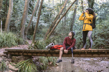 Backpacker couple taking photos with a camera on a break from hiking in a forest
