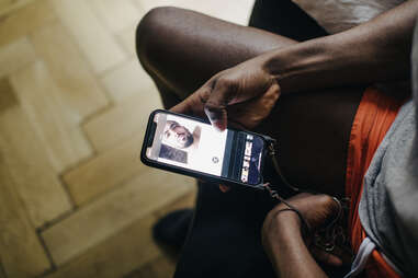 A man looking at different profiles on a gay dating app using his smartphone