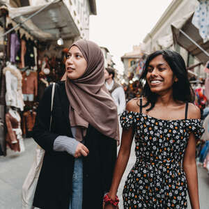 Two friends are walking in San Lorenzo market in Florence, Italy. They are shopping together.