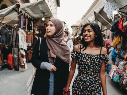 Two friends are walking in San Lorenzo market in Florence, Italy. They are shopping together.