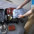 A man packing his small carry-on suitcase before a trip