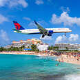 A plane flying overhead at a turquoise Maho Beach, SINT MAARTEN