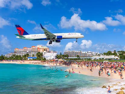 A plane flying overhead at a turquoise Maho Beach, SINT MAARTEN