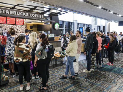 Long line of people waiting for coffee at airport Starbucks.