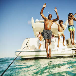 family diving off a boat into the sea