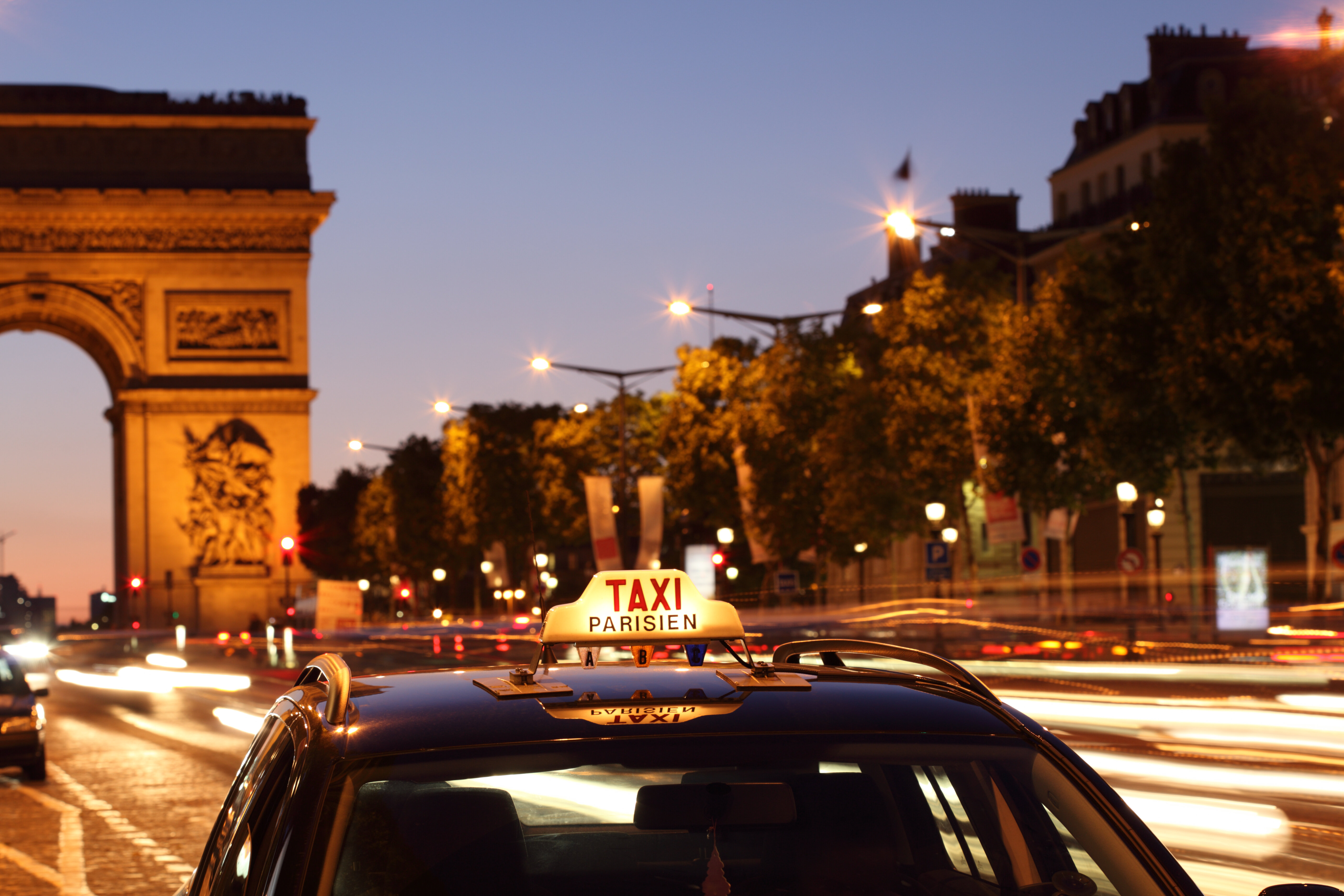 Paris taxi driving past Arc de Triomphe at dusk