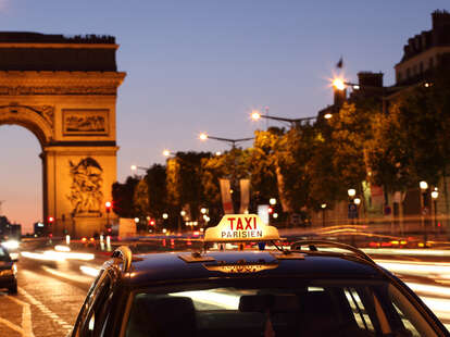 Paris taxi driving past Arc de Triomphe at dusk