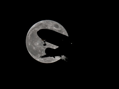 A passenger plane flies in front of the full ‘Hunter’s Moon’' as rises over the San Francisco Bay.