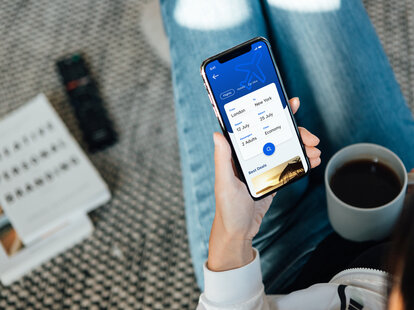 woman using smartphone to book flight tickets and plan holiday