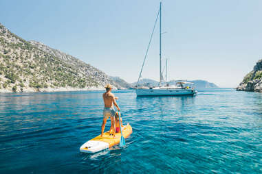 Young couple paddling on stand up paddleboards against the yacht in the sea