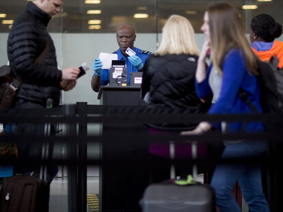 A Transportation Security Administration (TSA) officer checks a passenger’s identification at a security checkpoint.
