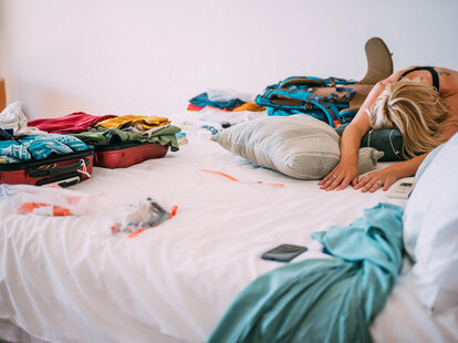 exhausted person on vacation dramatically resting on hotel bed