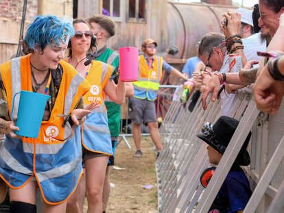 Oxfam Festival volunteers seen interacting with festival goers and filling water bottles at a Stage during the Fair Festival