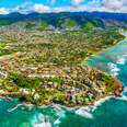 The suburban residential districts of Honolulu, Hawai'i along the coastline just outside of downtown from about 1000 feet over the Pacific Ocean.