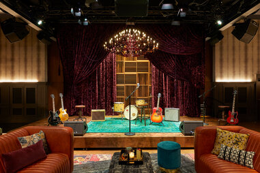 a small empty venue with instruments on a stage and couches