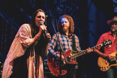 a woman singing into a microphone in front of a band