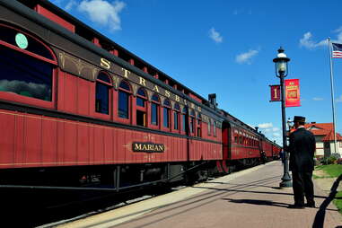 a man standing by a Strasburg Railroad train