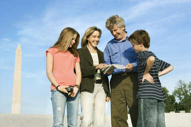 family in front of washington memorial in dc looking at guide book