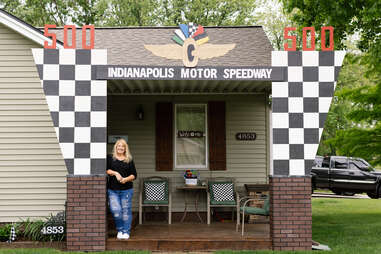 a woman stands in front of a house that looks like the entrance to the Indianapolis Motor Speedway