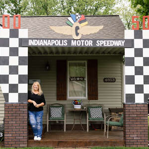 a woman stands in front of a house that looks like the entrance to the Indianapolis Motor Speedway