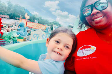 woman posing with child shes babysitting on the tea cups in disney world