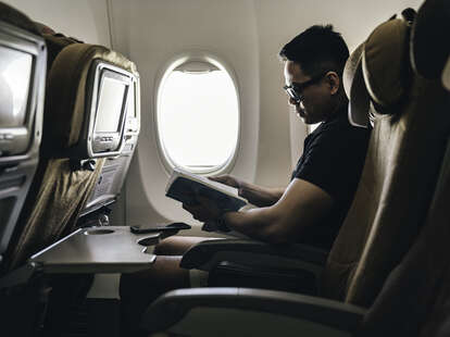 Man reading a book on airplane.