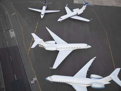 multiple private jets waiting on runway